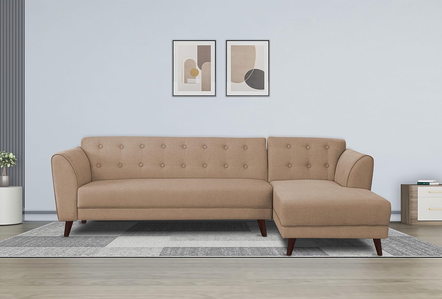 A beige colored 5 seater corner sofa with a right-hand side configuration, featuring a chaise longue, placed in a room with a light-colored wall and two framed artworks on the wall.